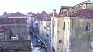 A narrow canal flanked by buildings with terracotta roofs and balconies. - At Home A Palazzo (Venice)