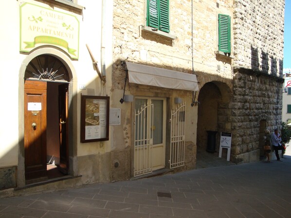 A building with a sign for 'Cameri Apartments' and a wooden door. - Elio Pistolesi (Radda in Chianti)