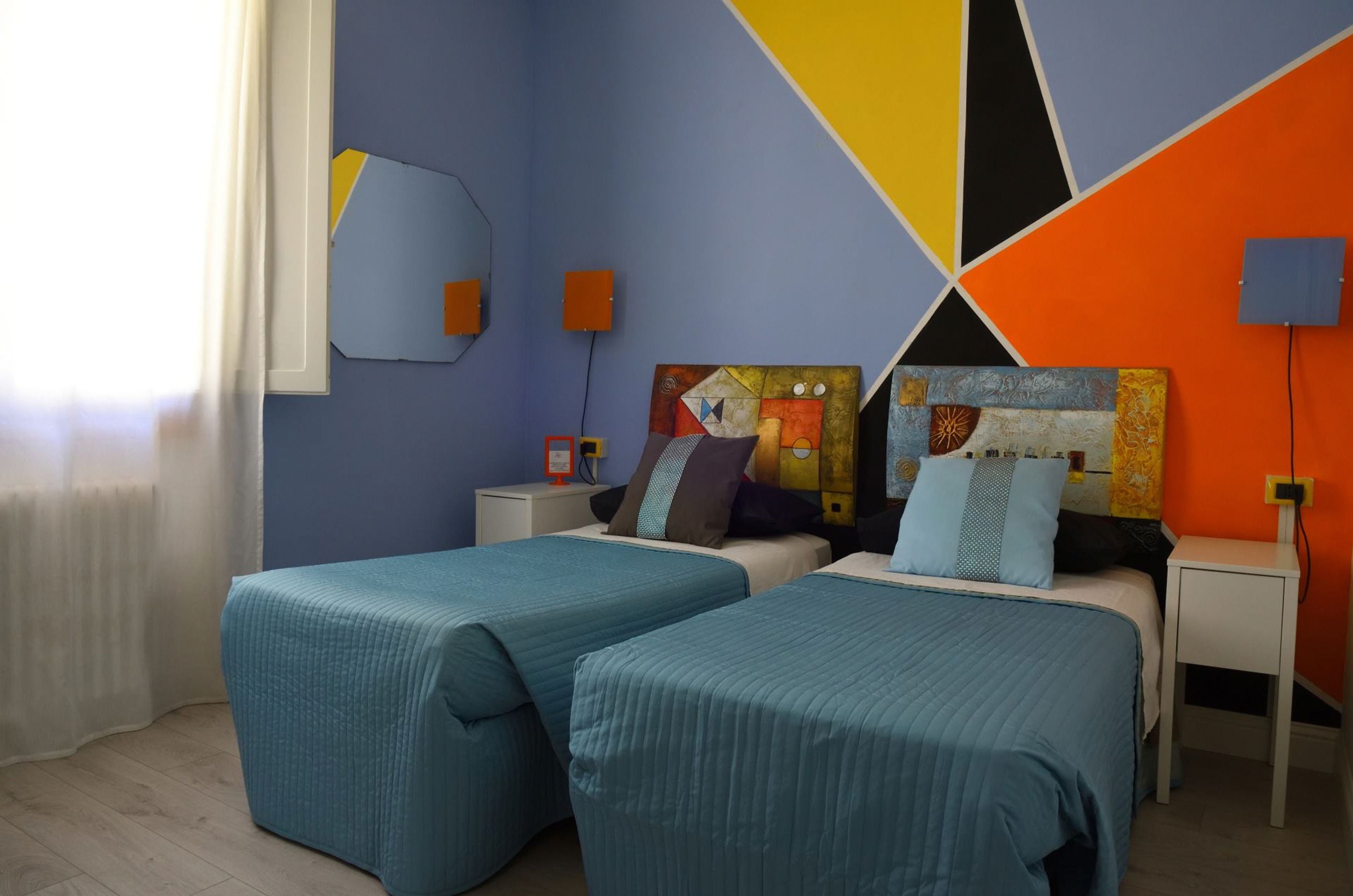 Una habitación con dos camas, una mesita de noche, un reloj de pared y un cuadro.