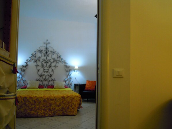 A bedroom with a bed, a wall-mounted decorative metal piece, a nightstand, and a lamp.
