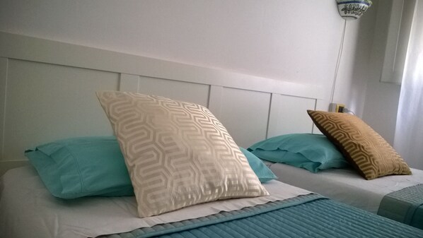 A bed with patterned pillows and a blue quilt.