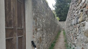 A narrow stone pathway flanked by old stone walls and a wooden door. - Leonardo's Rooms (Pontassieve)