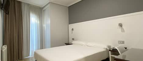 Una habitación de hotel con una cama, mesitas de noche, un escritorio y una silla.