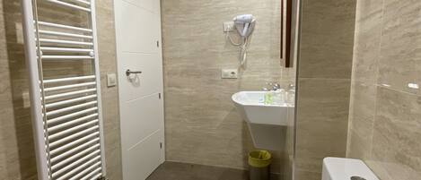 A bathroom with a toilet, a sink, a towel rack, and a hairdryer.