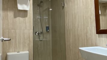 Un baño moderno con ducha envuelta en vidrio, inodoro blanco y lavamanos.