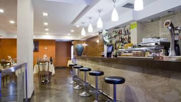 A bar area with multiple stools, a counter with various bottles, and a marble floor.