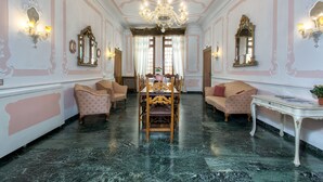 Ein Zimmer mit Esstisch, Stühlen, einer Chandelüster und zwei Sofas.