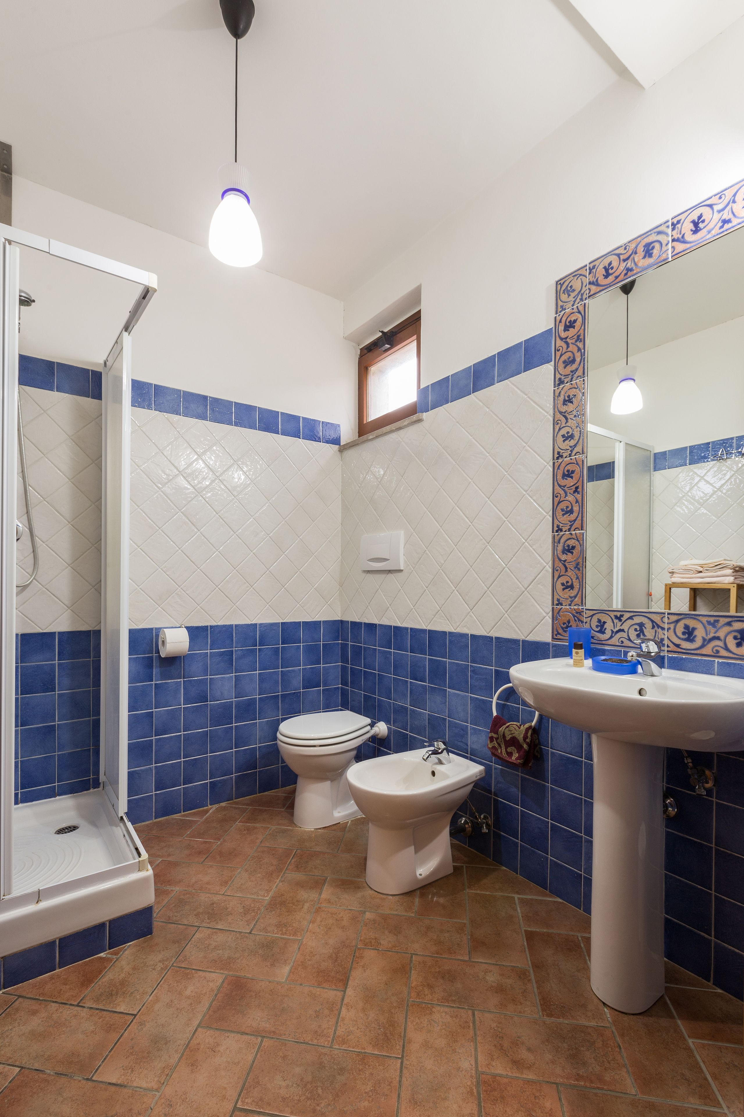 Un bagno con doccia, due servizi igienici, un lavandino e uno specchio.