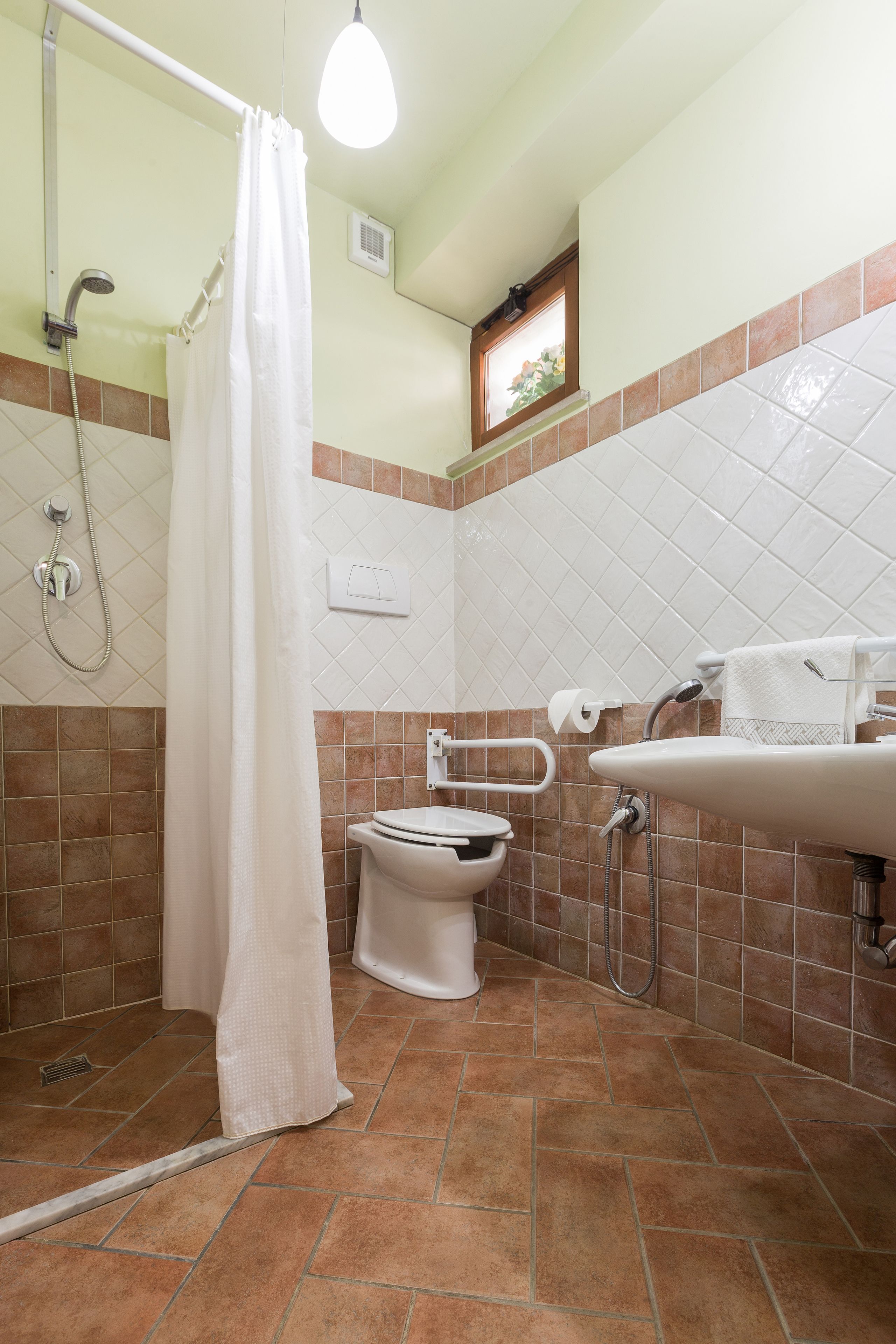 Casa de banho com chuveiro, sanita e lavatório.