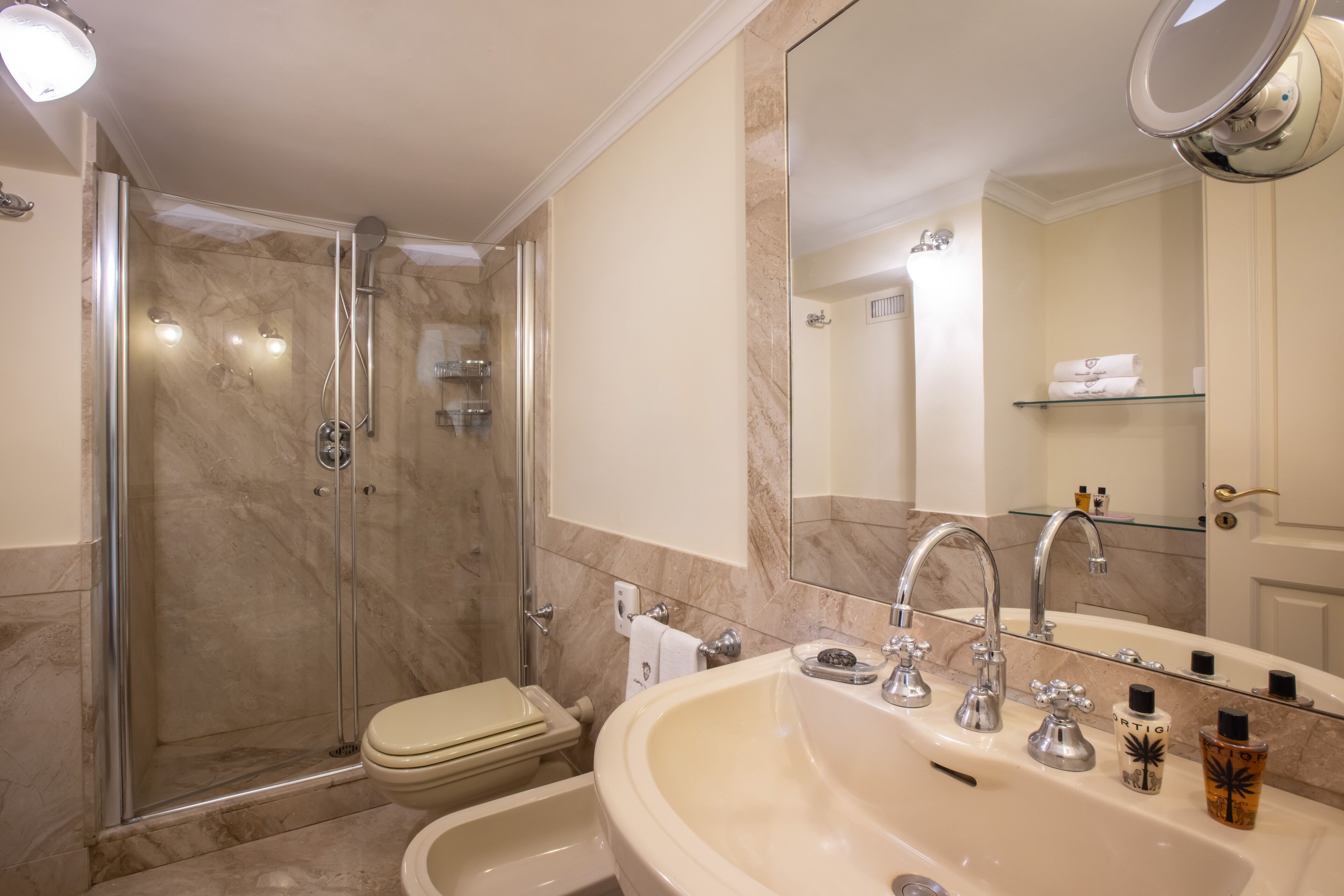 Une salle de bain équipée d’une douche, de toilettes, d’un lavabo et d’un grand miroir.