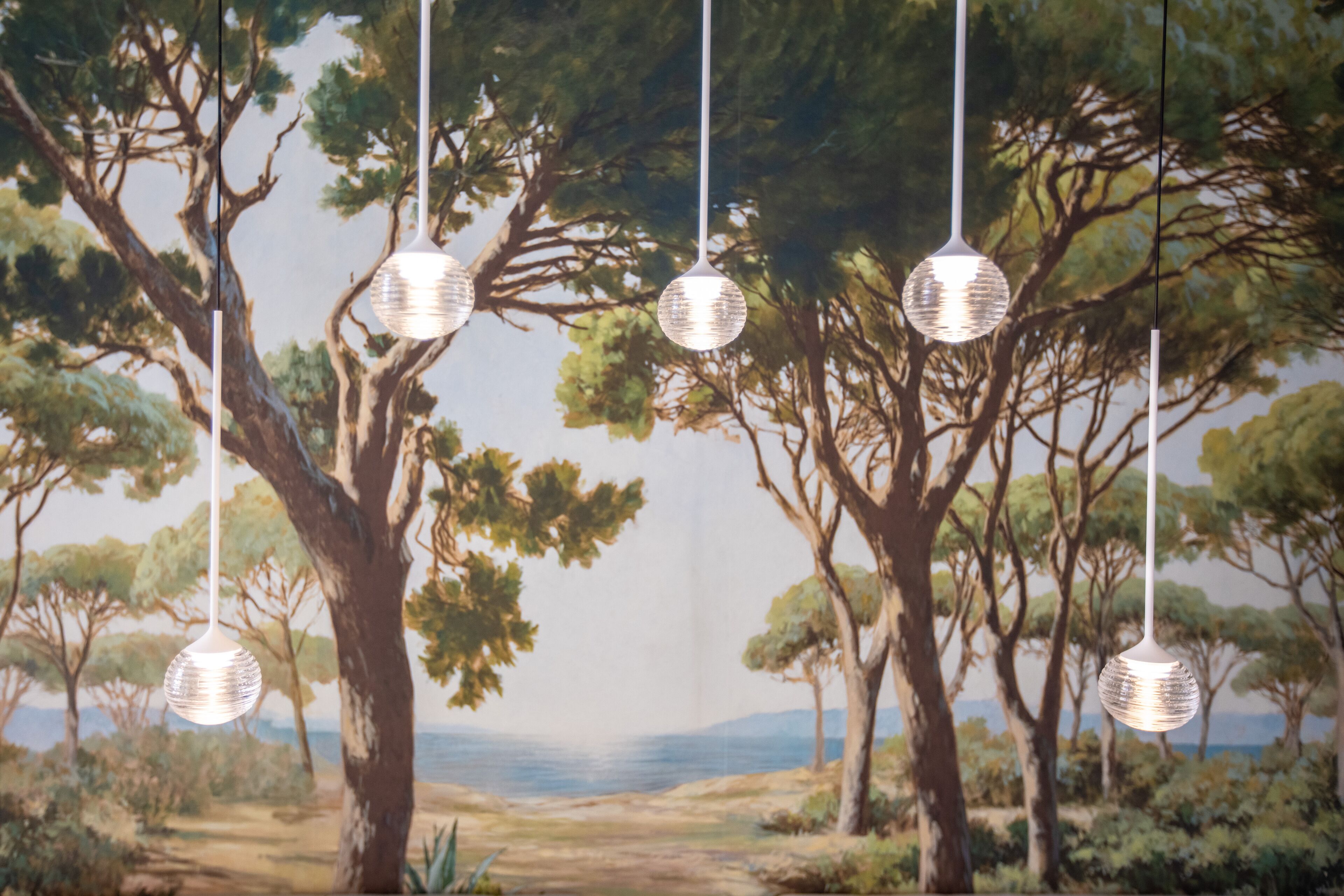 A room with a mural of trees and a view of the sea.