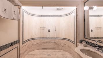 Een badkamer met een douche, wastafel en spiegel.