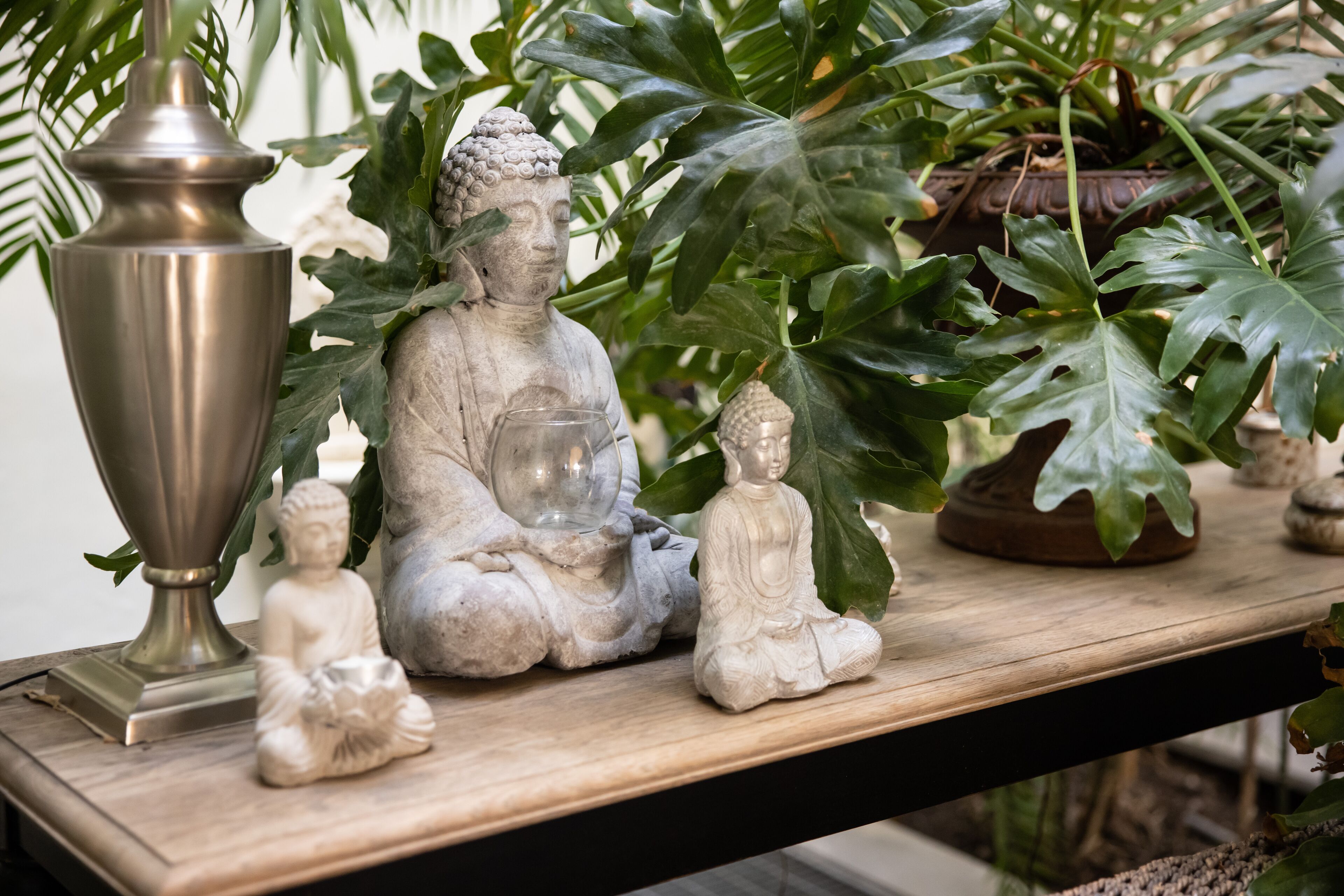 Uma prateleira com uma estátua de Buda, uma pequena estátua de Buda e um vaso decorativo.