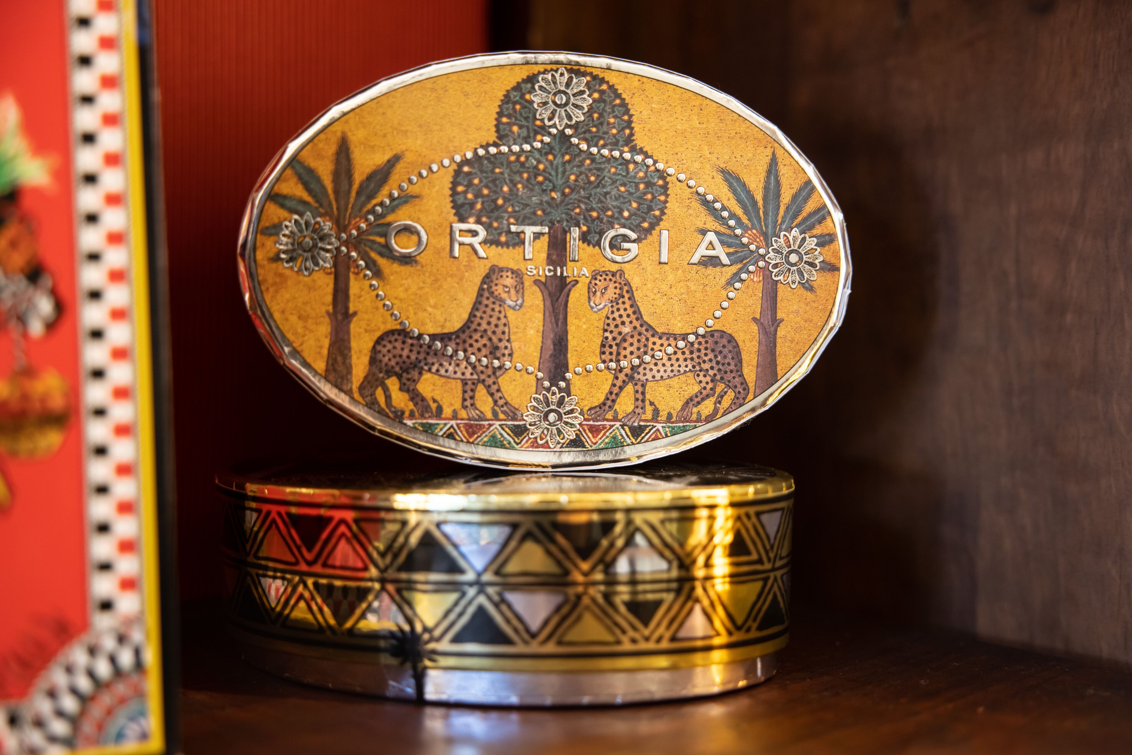 Un contenitore decorativo con l'etichetta "ORTIGIA SICILIA" e due disegni di leopardo.