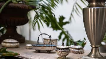Une table en bois, ornée de services à thé anciens et surmontée d’une grande urne en métal.