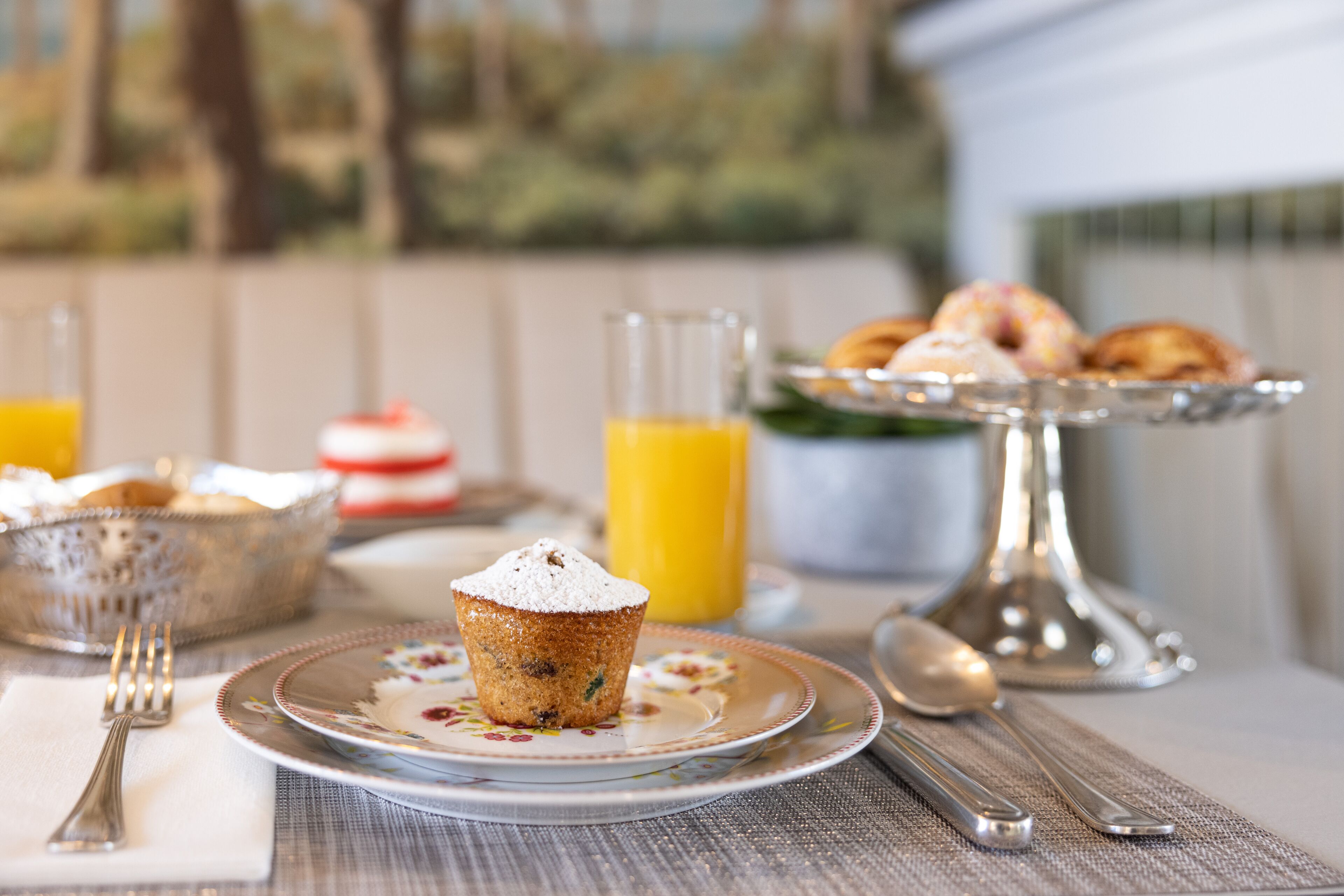 Ein Frühstückstisch mit einem Muffin, Croissants und Orangensaft.