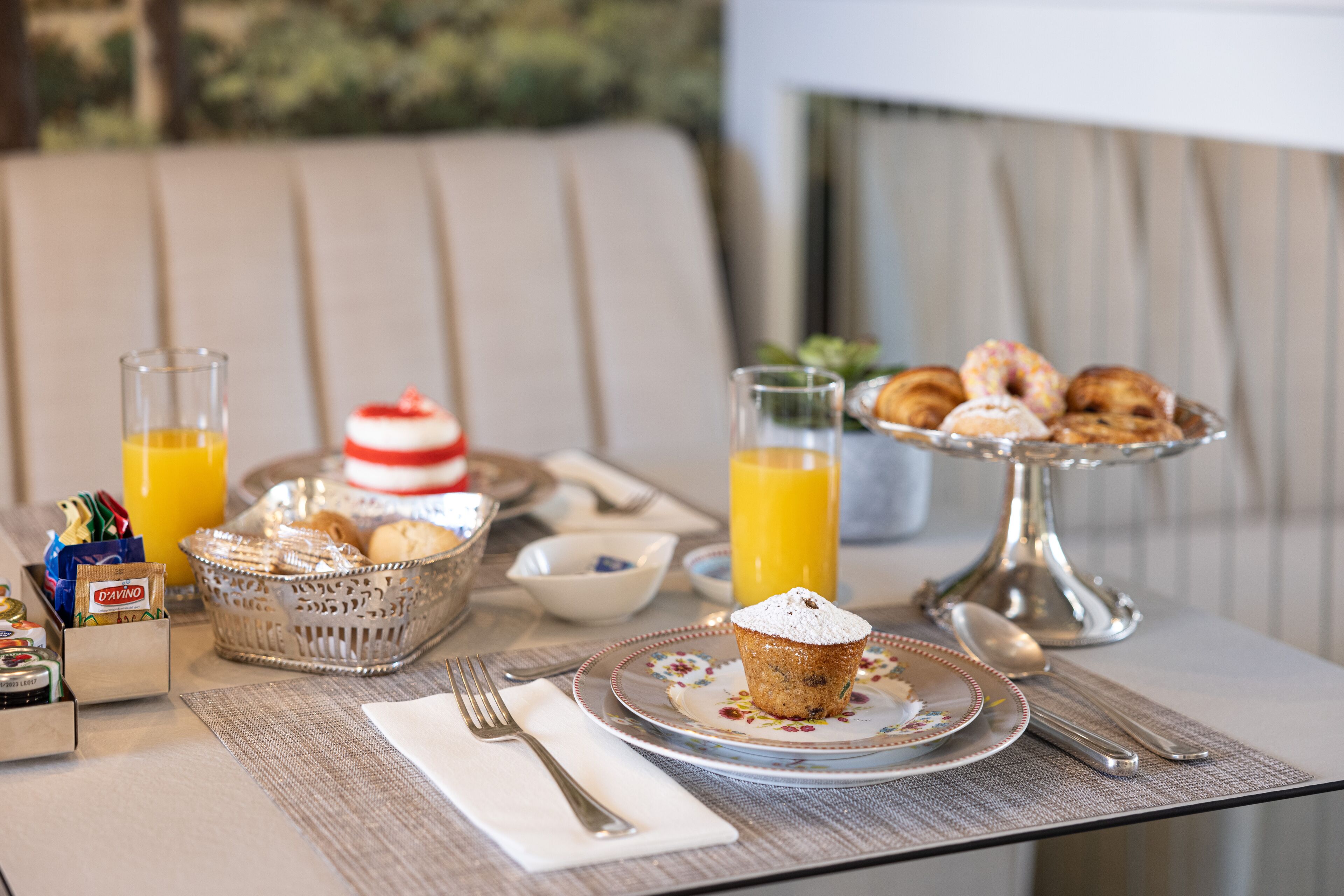 Ein Frühstückstisch mit Gebäck, einem Muffin und Orangensaft.