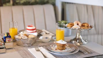 Ein Frühstückstisch mit Gebäck, einem Muffin und Orangensaft.