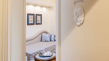 A cozy room with a sofa, a small round table with a tray, and two framed artworks on the wall.