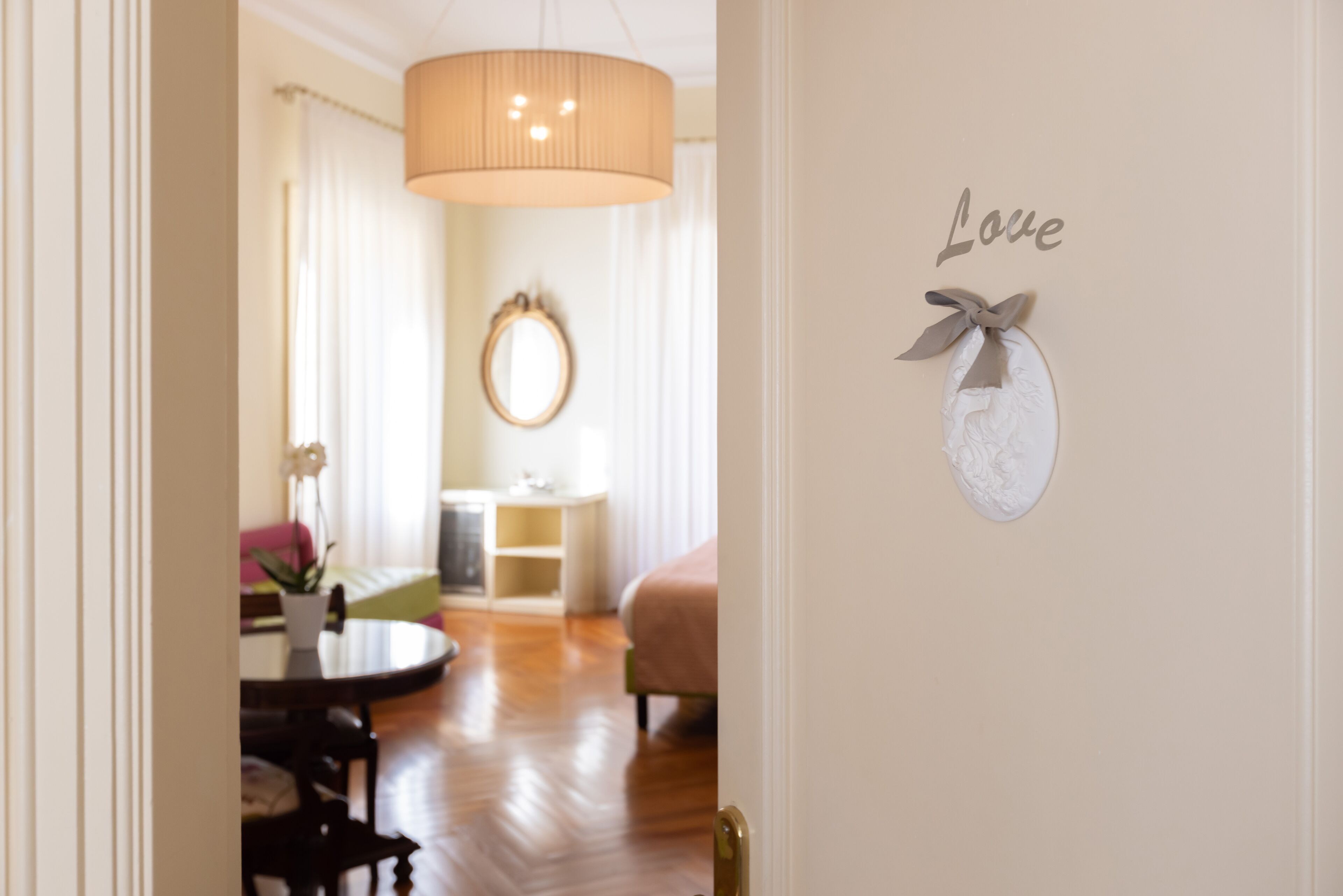 Ein Hotelzimmer mit einem Bett, einem runden Tisch, einem Stuhl, einer Zimmerpflanze und einer Wand mit dem Schriftzug 'Love'.