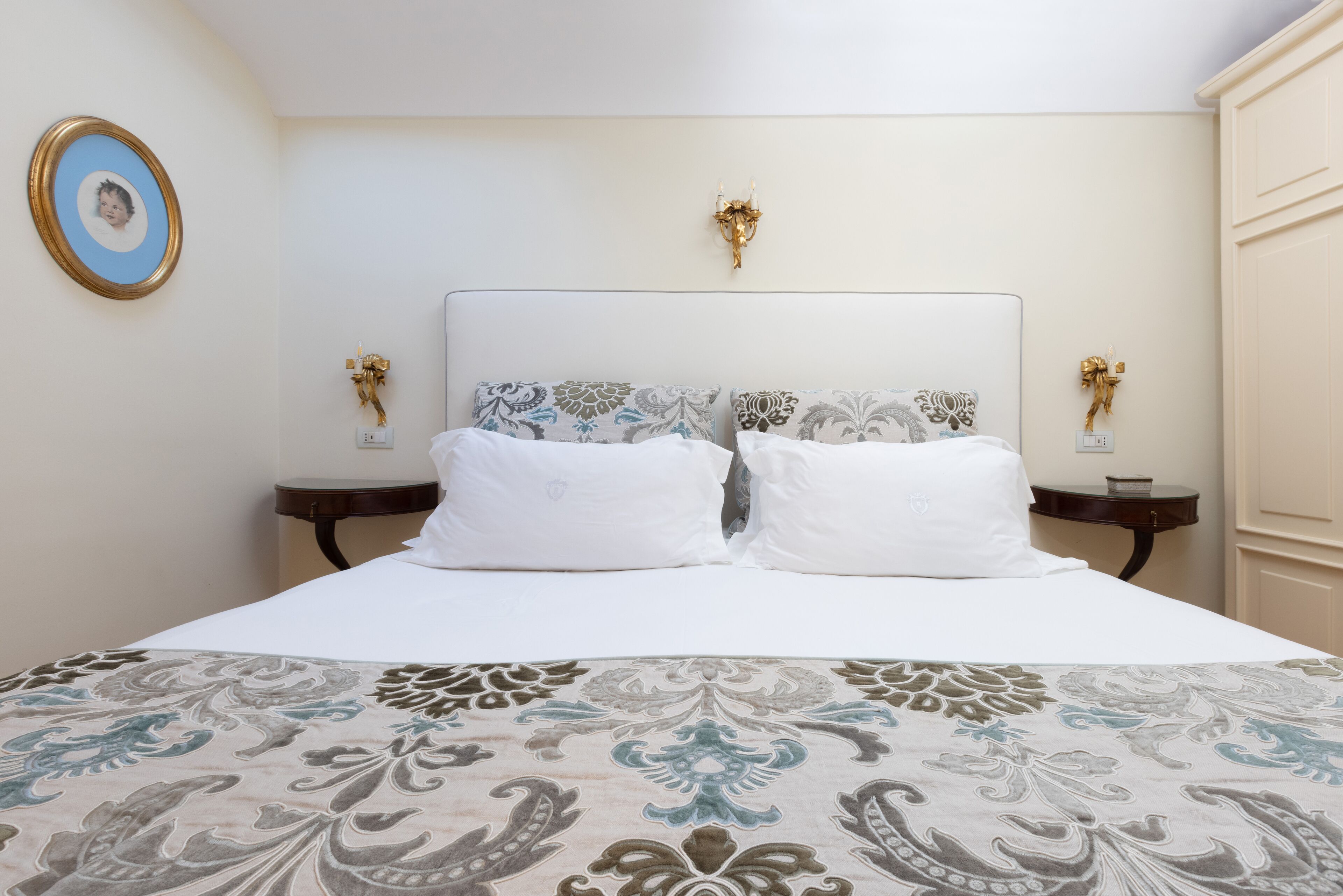 A neatly made bed with a patterned bedspread, two white pillows, and a decorative headboard.
