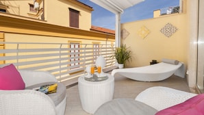 Un espacio al aire libre iluminado por el sol con mobiliario de mimbre, una pequeña mesa con bebidas y azulejos decorativos en la pared.