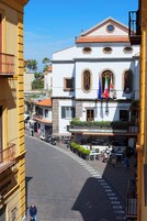 A street view with a building featuring a balcony with outdoor seating, a sign reading "Ristorante Al Volto," and flags.