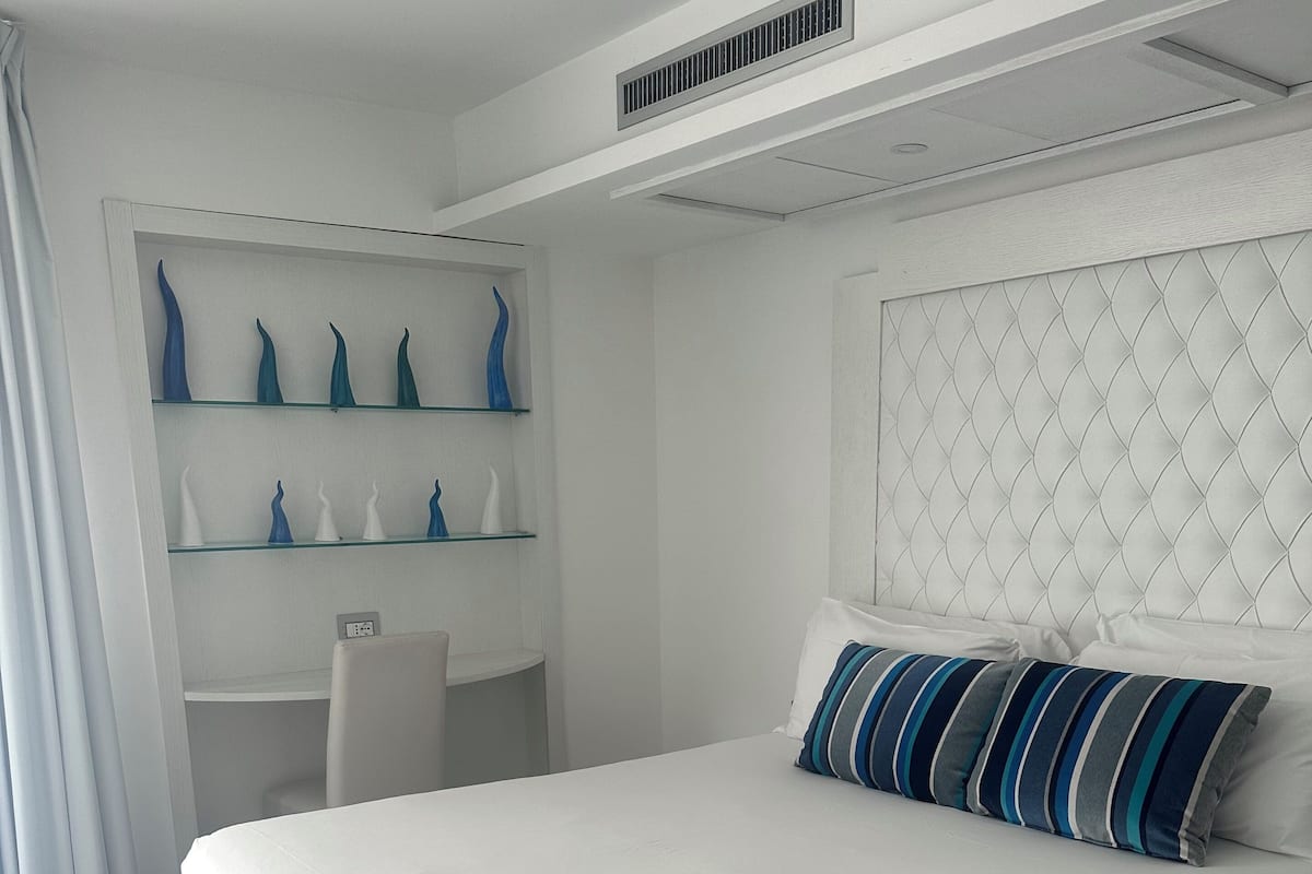 Un dormitorio moderno con una cama grande, un escritorio y jarrones decorativos en estantes.