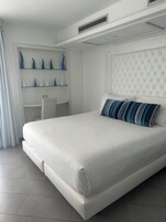 Un dormitorio moderno con una cama grande, un escritorio y jarrones decorativos en estantes.