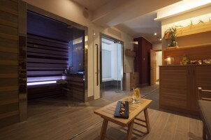 A modern hotel room with a wooden floor, a glass door leading to a balcony, and a small wooden table with a tray of snacks.
