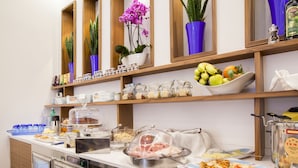 Montaje de bufé con diversos alimentos, un refrigerador y plantas decorativas.
