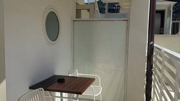 Un balcon avec une table et des chaises, une vue sur le ciel et une balustrade blanche.
