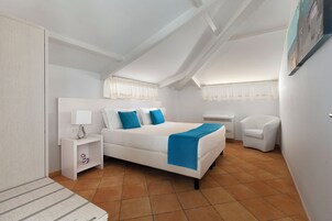 Un dormitorio con cama, mesita de noche, silla y ventana con cortinas.