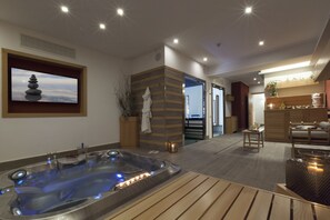Un spa moderno con bañera de hidromasaje, suelo de madera, televisor montado en la pared y una decoración tranquila.
