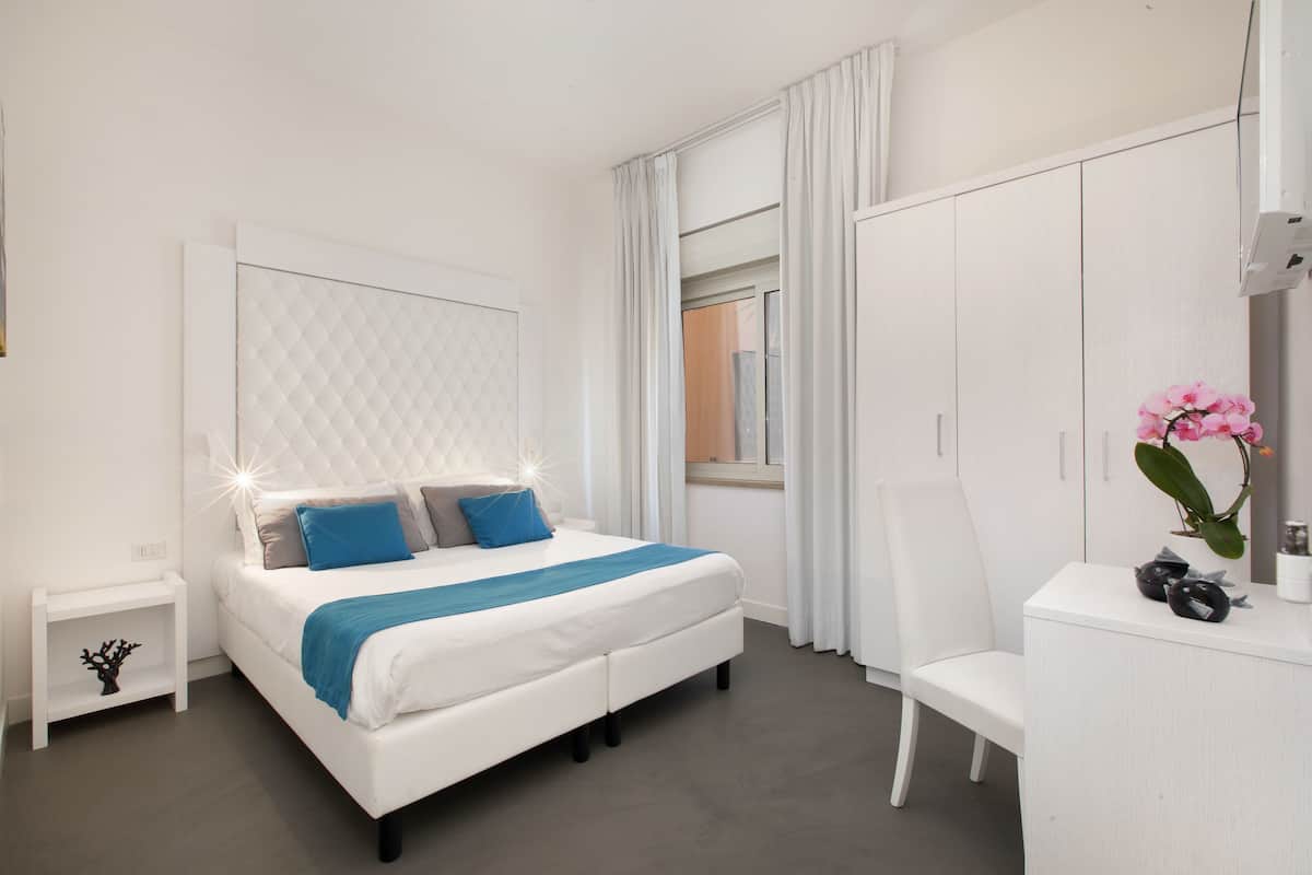 Un dormitorio moderno con cama, mesita de noche, cómoda y ventana con cortinas.