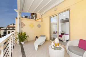 A balcony with a white sofa, a small table with a glass, and a potted plant.