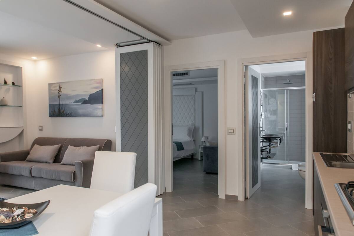 Una sala moderna con sofá, una mesa de comedor y una zona de cocina con estufa.
