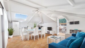 Un espacio habitable moderno con comedor, cocina y una zona de estar acogedora con un sofá azul.