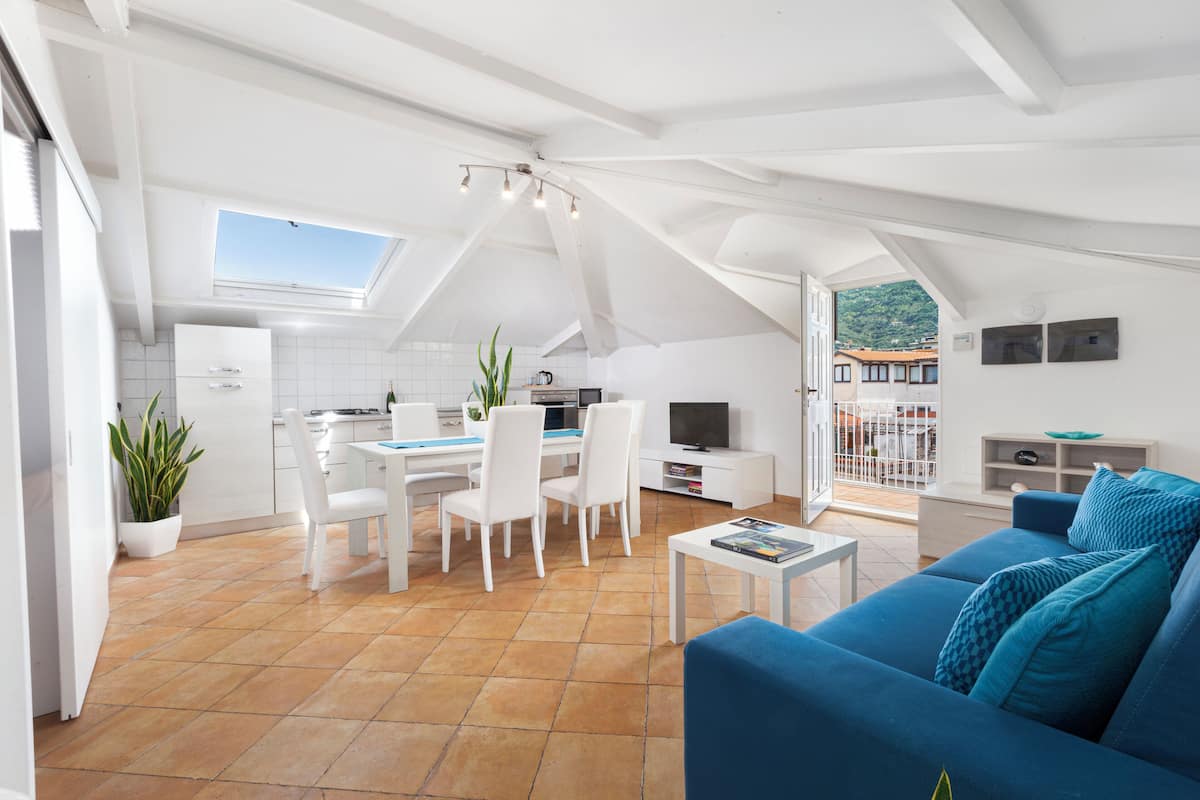 Un espacio habitable moderno con comedor, cocina y una zona de estar acogedora con un sofá azul.