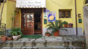 A yellow building with a wooden door and a sign reading "Locanda 'dalla Compagnia'". - Locanda dalla Compagnia (Riomaggiore)