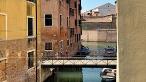 A narrow canal with buildings on either side, a bridge, and boats docked along the water. - Locanda del Ghetto (Venice)