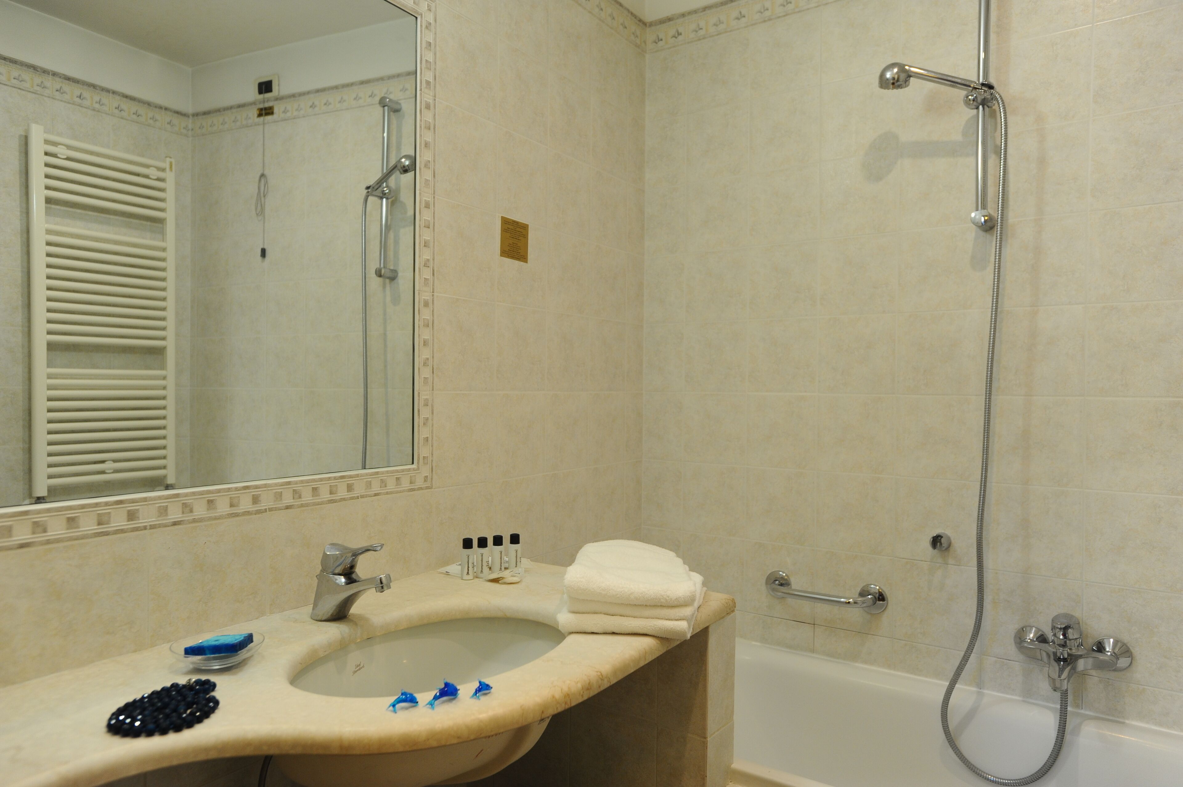 Ein Badezimmer mit Waschbecken, Spiegel, Handtuchhalter und Dusche.
