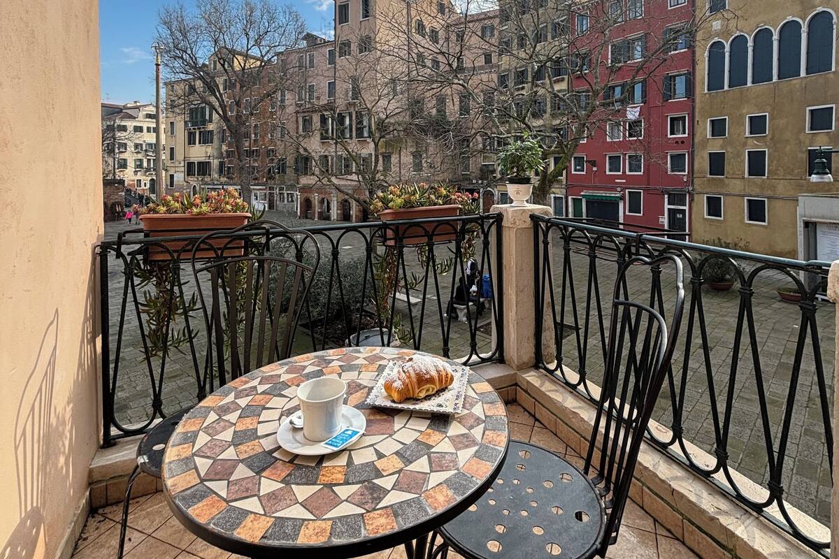 A balcony with a tiled table, chairs, and a croissant.