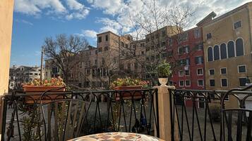 Un tavolo rotondo con un croissant e una tazza, con vista su un cortile con edifici e cielo sereno.