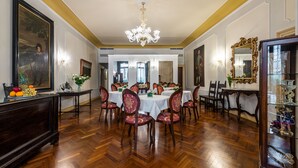 A formal dining room with wooden flooring, white tables, and red upholstered chairs. - Locanda Sant'Agostin (Venice)