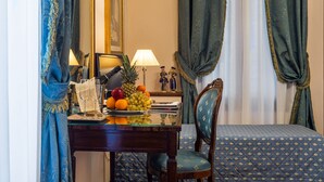 A hotel room with a bed, a desk with a fruit bowl, a lamp, and a chair. - Locanda Sant'Agostin (Venice)