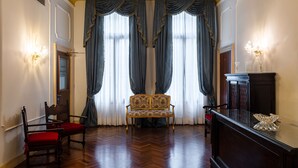 A room with a wooden floor, a sofa, a chair, a cabinet, and a door. - Locanda Sant'Agostin (Venice)