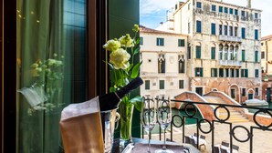 A balcony with a table set for two, a bottle of champagne, and a vase of flowers. - Locanda Sant'Agostin (Venice)