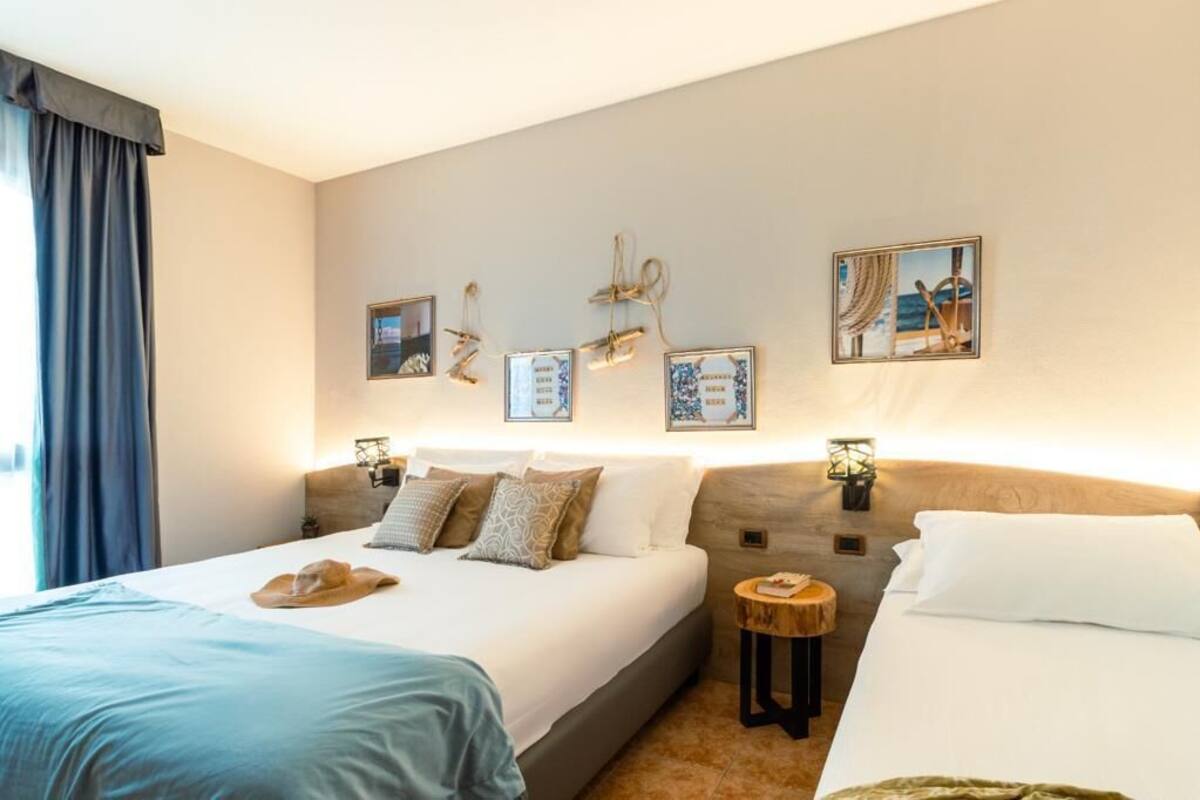 A hotel room with a large bed, two bedside tables, and wall-mounted artwork.