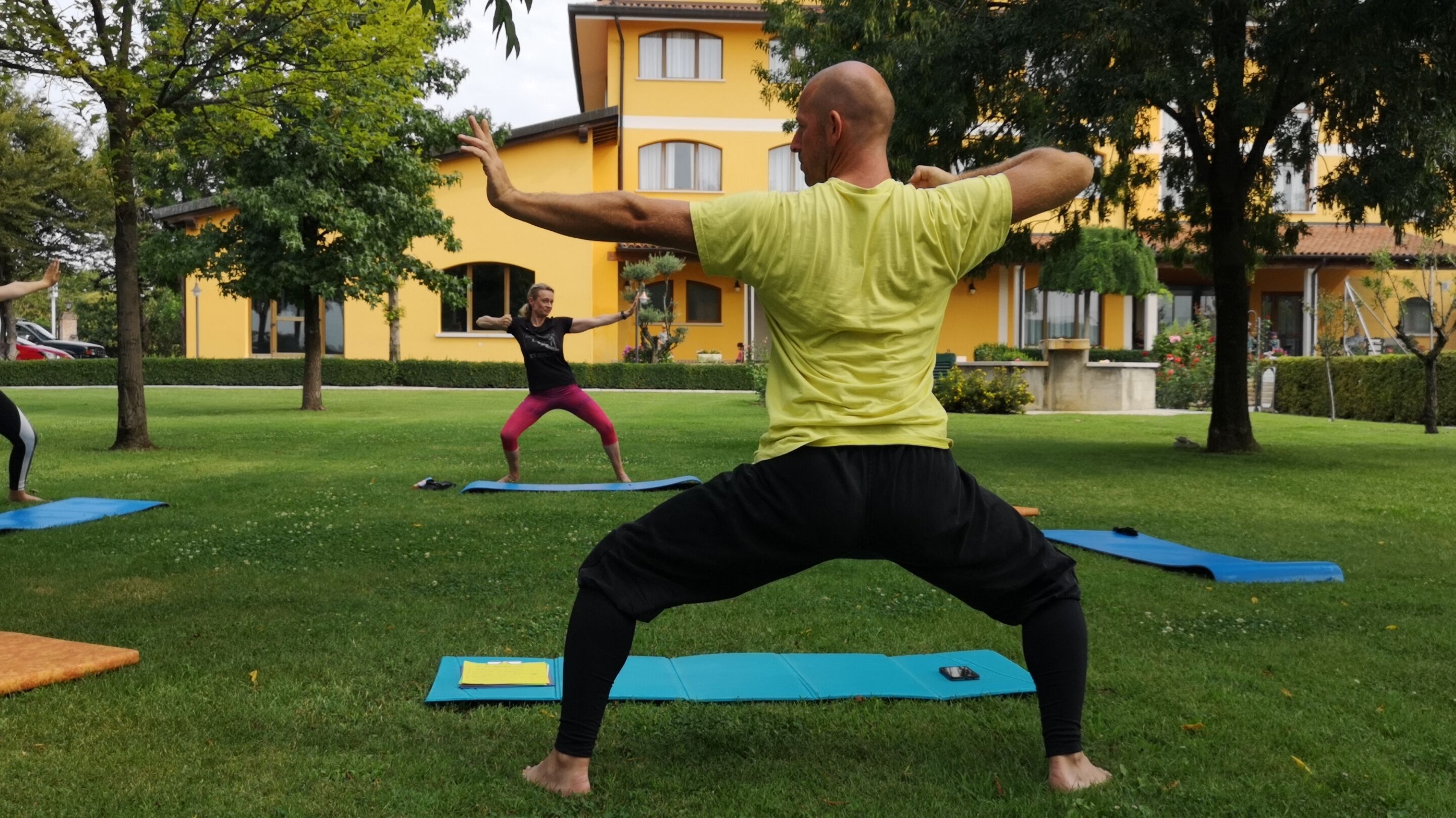 Un parco con persone che praticano yoga su tappetini.